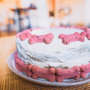 A dog friendly birthday cake with white icing and pink dog bones