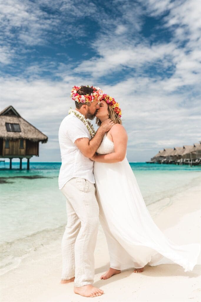 Blair and Brady kiss on a white sand beach after their vow renewal ceremony.