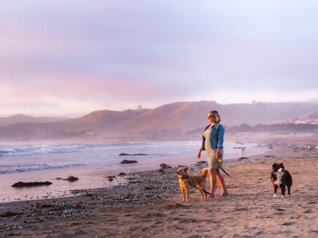 Blair stands on the beach at sunset in Morro Bay with her two dogs, June and Margot.