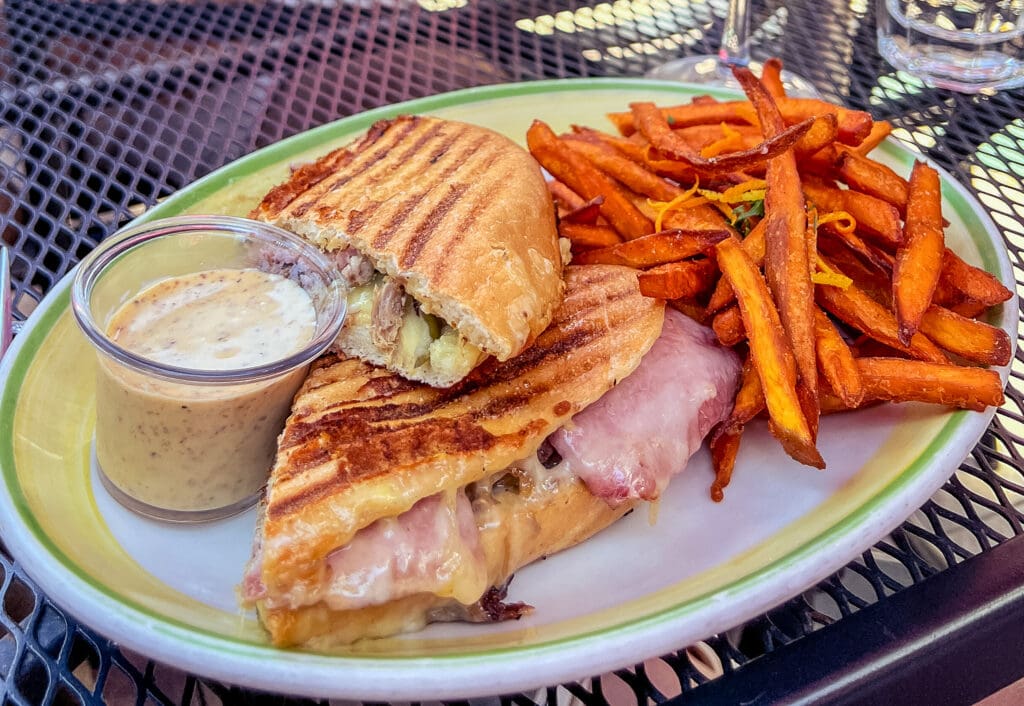 A close up photo of a grilled Cubano sandwich and sweet potato fries from Big Sky Cafe in San Luis Obispo.
